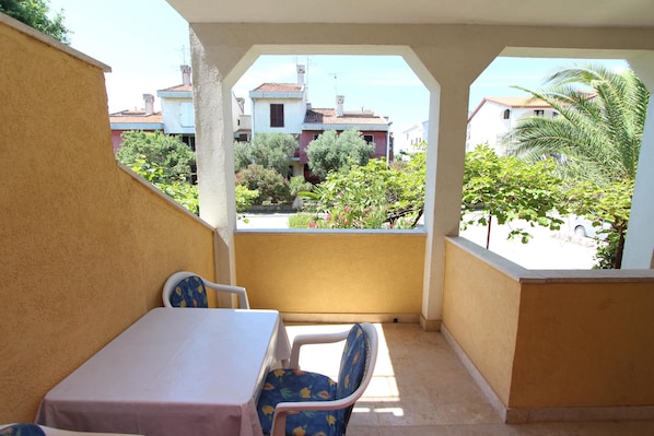 A balcony with a table and chairs, overlooking a residential area with houses and greenery.