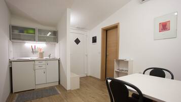 A compact kitchen with white cabinets, a wooden door, and a small dining area with a table and chairs.