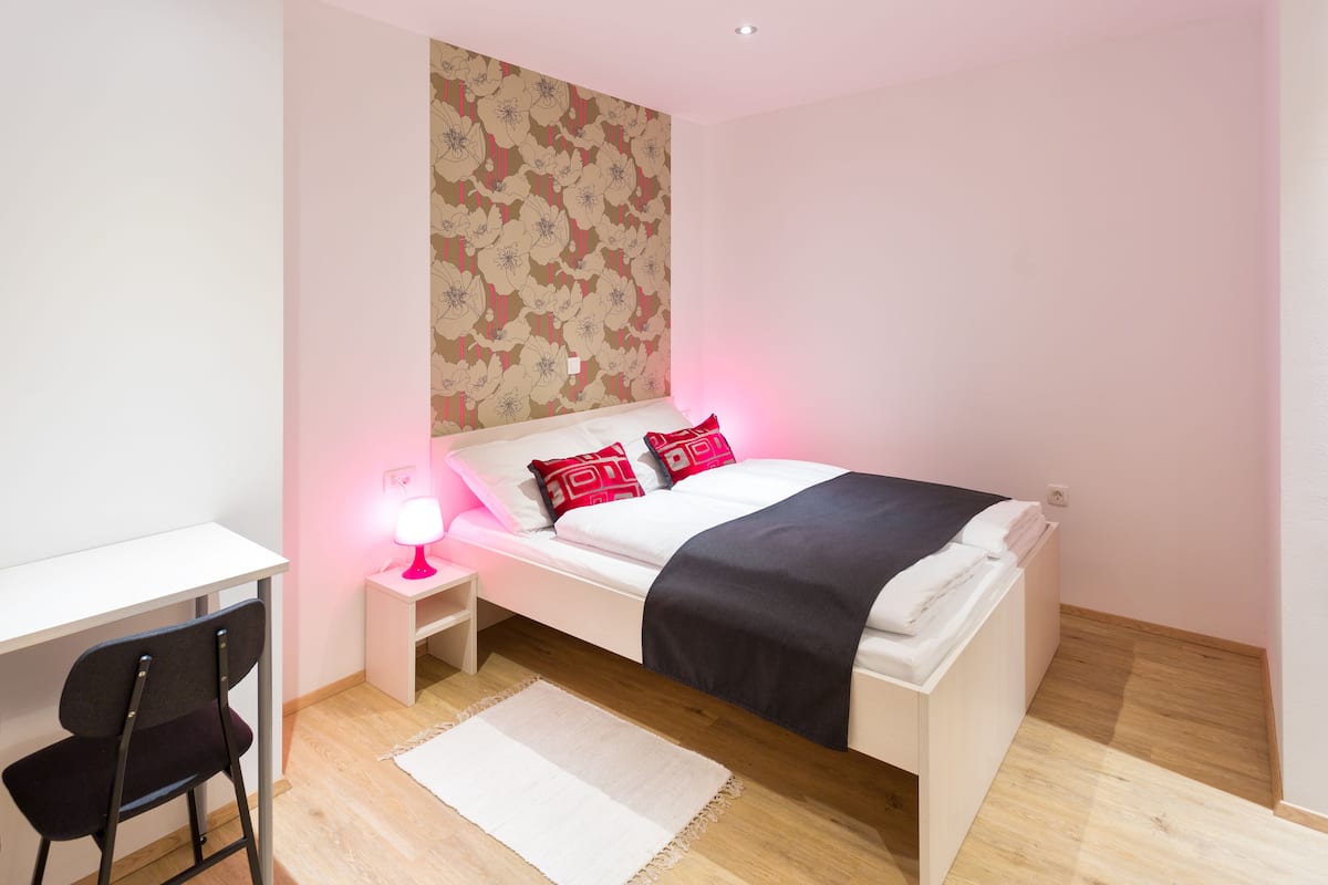Een slaapkamer met een bed, een bureau en een stoel.