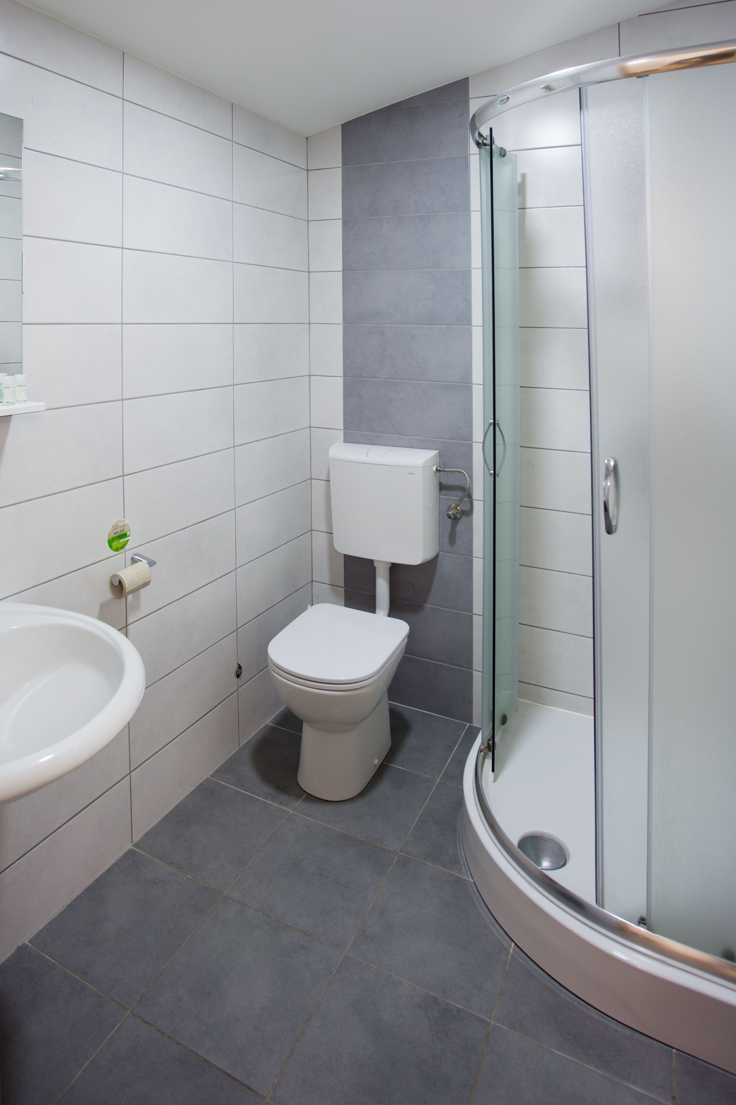 A bathroom with a toilet, sink, and glass shower enclosure.