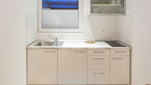 A kitchen with a window, sink, and cabinets. - Apartments SHISHKA (Ljubljana)