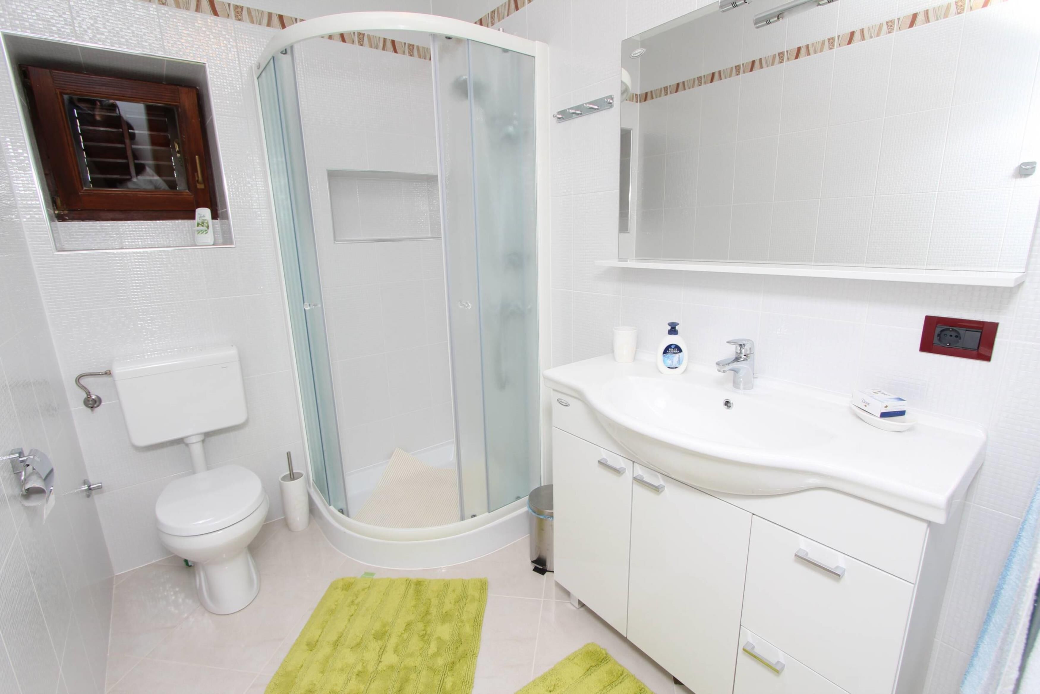 Un bagno con WC, doccia, lavandino e specchio.