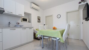 A compact kitchen with white cabinets, a microwave, a sink, and a dining area with a table and chairs.