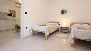 A bedroom with two single beds, a bedside table with a lamp, a small rug, and a wall-mounted picture.