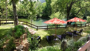 A fenced garden area with a wooden deck, outdoor seating, and a view of a river.