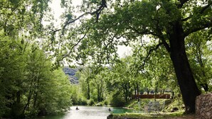 A river with boats, surrounded by trees and a stone wall.