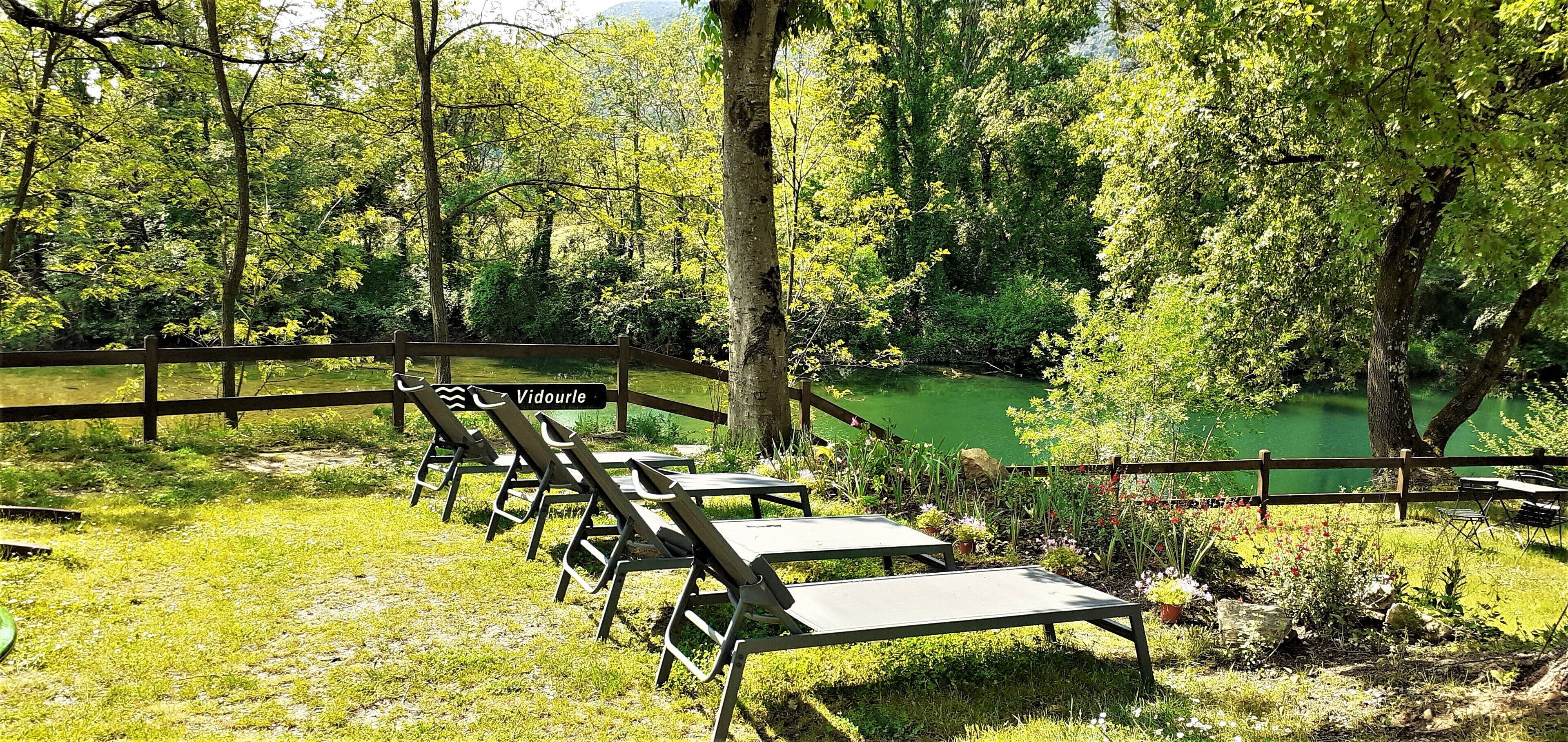 A serene outdoor area with wooden benches and a sign reading "Vidourle."