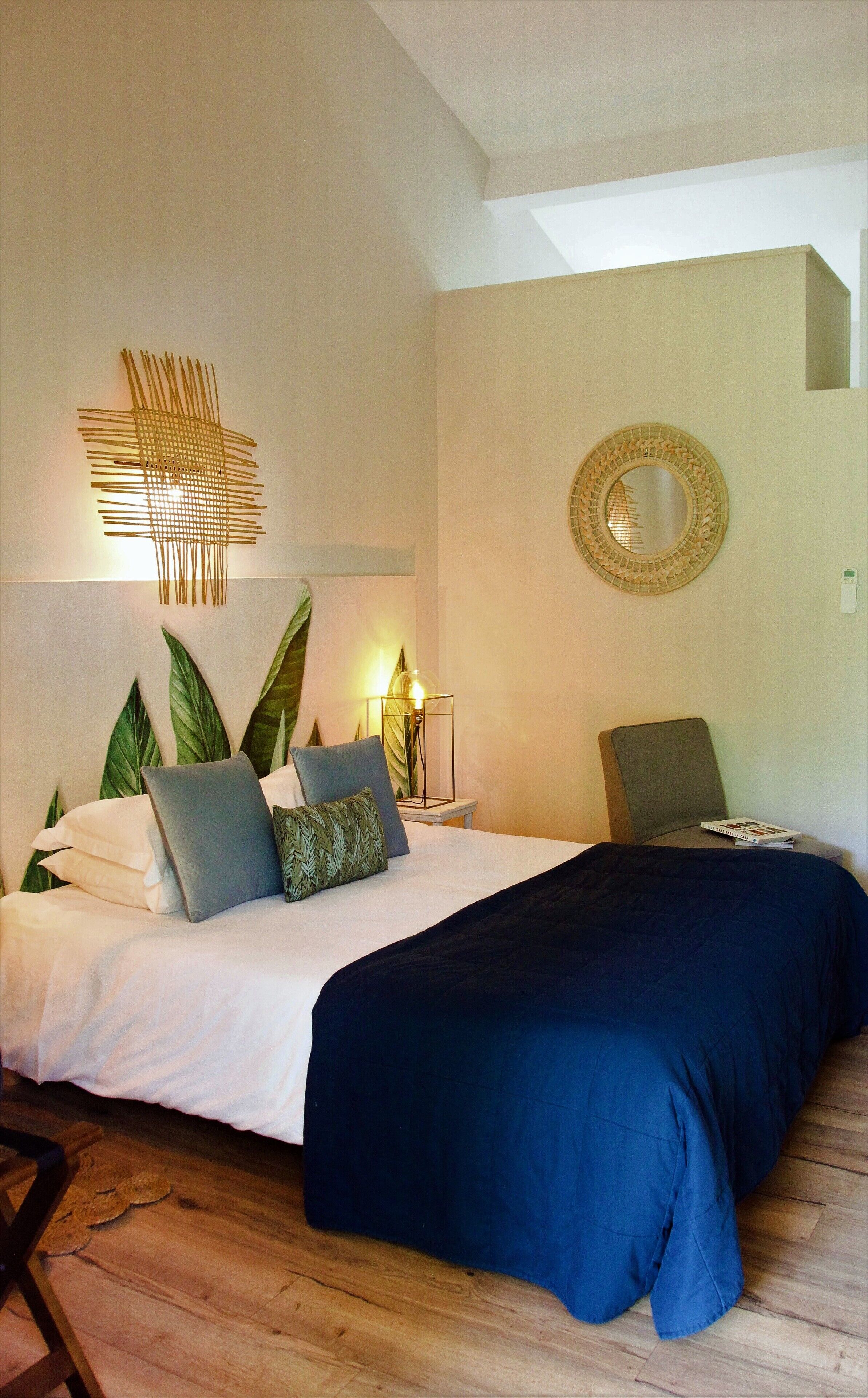 Un dormitorio con cama, una lámpara de noche, un espejo y una obra de arte en la pared.