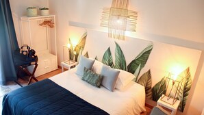 A neatly made bed with a dark blue bedspread, two pillows, and a nightstand with a lamp.