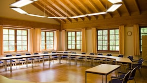 A conference room with long tables and chairs, large windows, and wooden beams on the ceiling. - Naturfreundehaus Rahnenhof (Carlsberg)