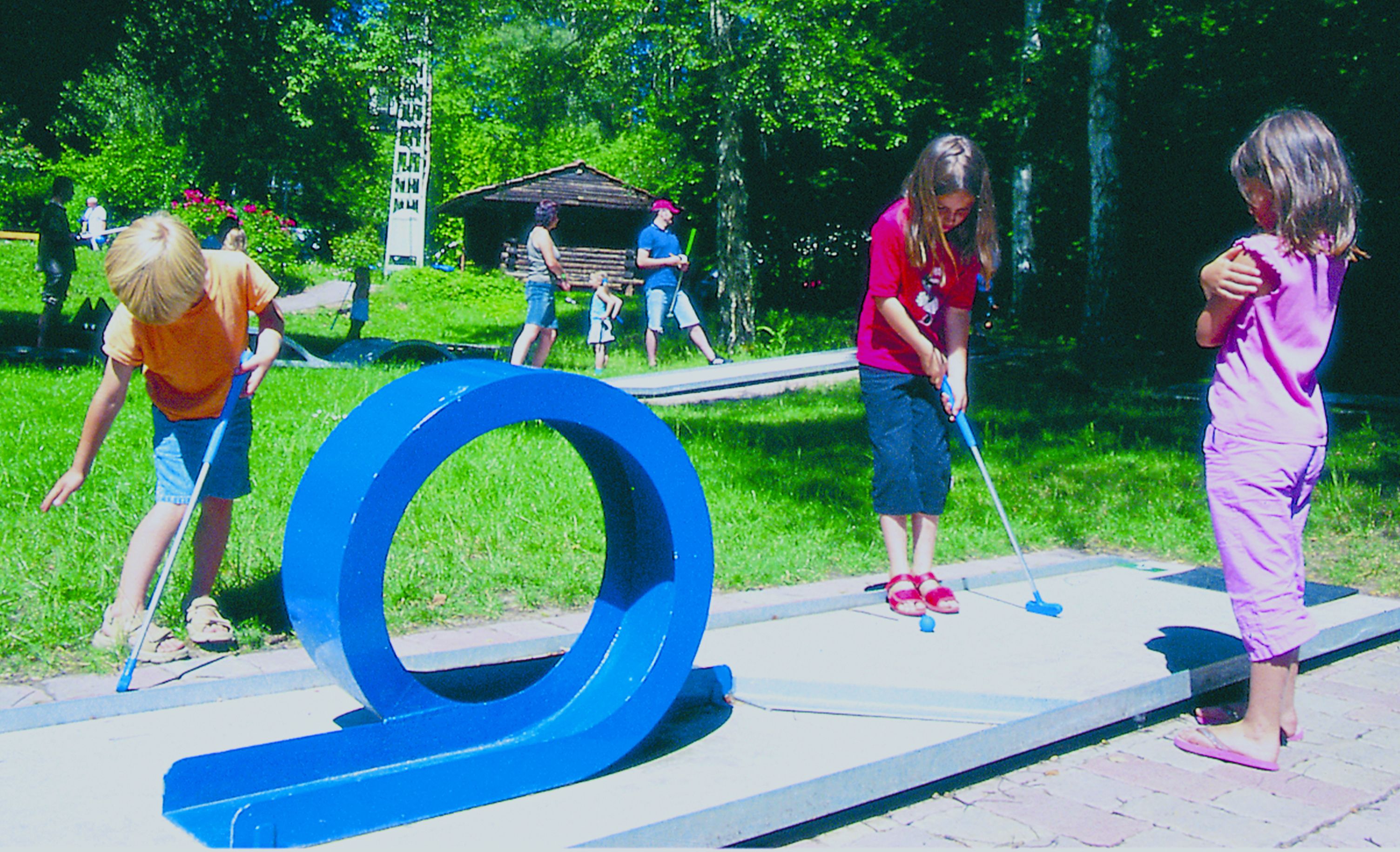 A playground with a blue circular structure, a small shelter, and a paved area.