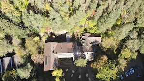 An aerial view of a house surrounded by dense forest, with a parking area and a small driveway leading to the entrance. - Naturfreundehaus Rahnenhof (Carlsberg)