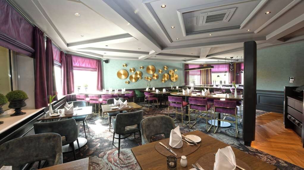 A restaurant with a modern interior, featuring a mix of seating arrangements and a decorative wall with circular patterns.