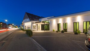 Un hôtel doté d’une façade moderne, d’une entrée couverte et d’une allée pavée.