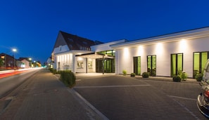 A hotel with a modern facade, a covered entrance, and a paved driveway.