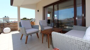 A balcony with wicker furniture, a table, and a glass door leading to an indoor area. - Apartments Makado (Rovinj)