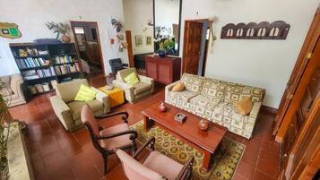 Una sala de estar con un sofá, sillones, una mesa de centro, una estantería y una puerta.