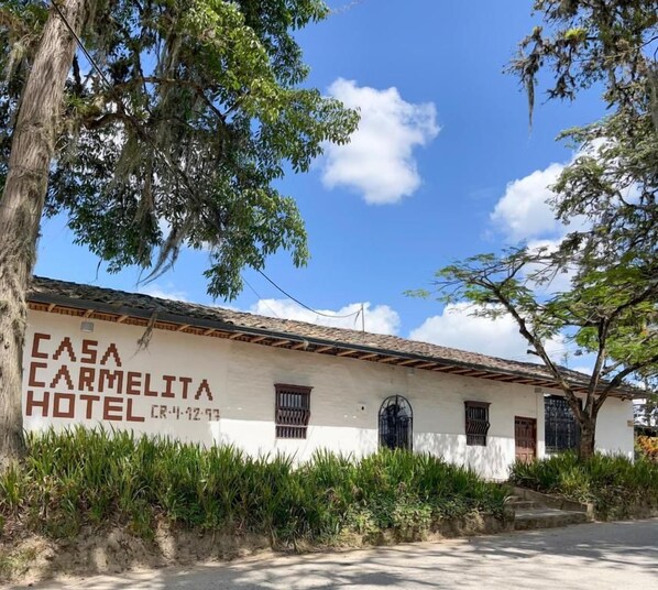 Un edificio blanco con un letrero que dice 'CASA CARMELITA HOTEL'.