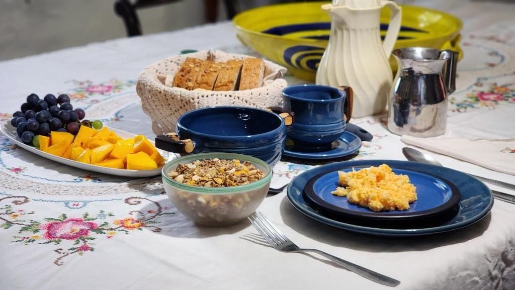 A table set with various food items including fruits, bread, and a bowl of granola.