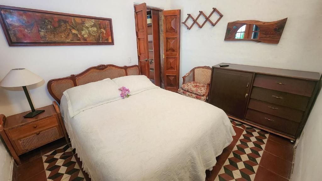 A bedroom with a bed, a nightstand, a dresser, a chair, and a painting on the wall.
