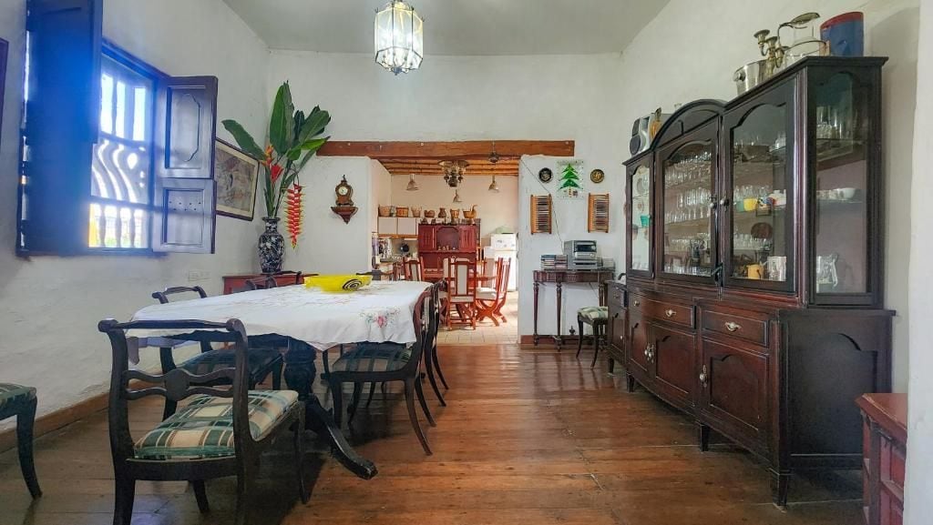 Un comedor con una mesa de madera, sillas, un armario y un colgador de luz.