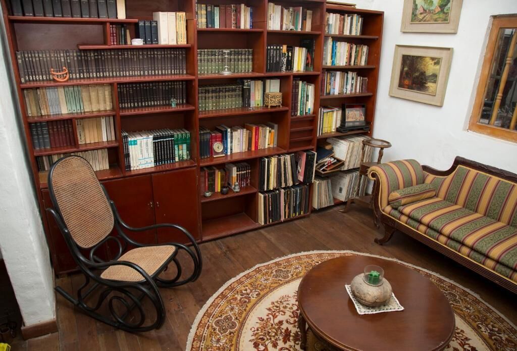 A room with a bookshelf, a rocking chair, a sofa, and a coffee table.