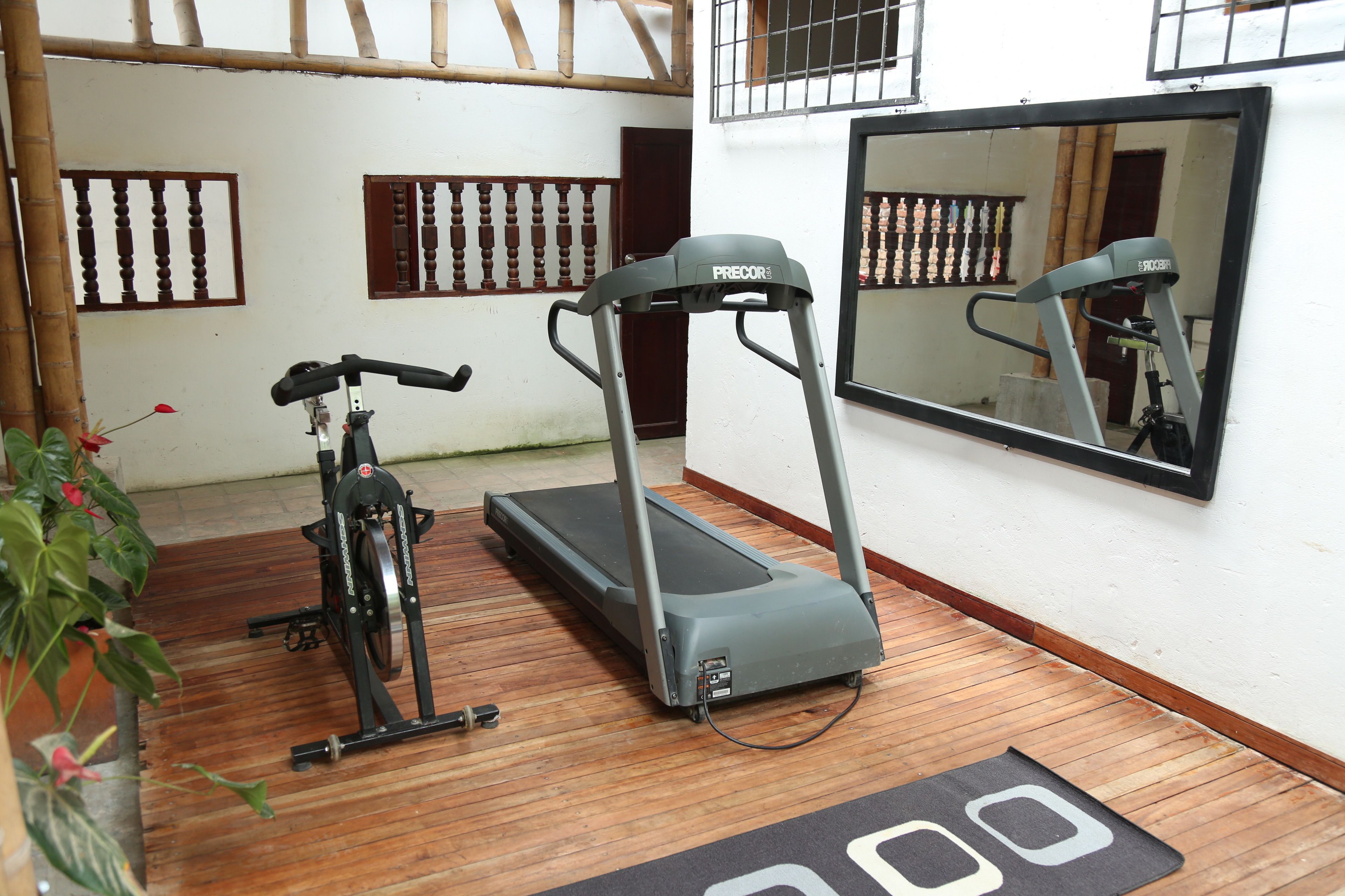 Ein Raum mit Laufband, Ergometer und einem großen Spiegel an der Wand.