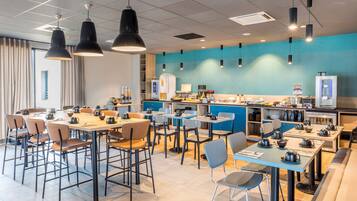 Una cafetería moderna con varias zonas de estar, incluidas mesas y sillas, y una barra con máquinas de café.