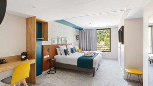 Une chambre d’hôtel moderne équipée d’un lit, d’un bureau, d’une chaise et d’un téléviseur.