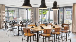 Un espace de restauration moderne avec des tables rondes, des chaises et des luminaires suspendus.