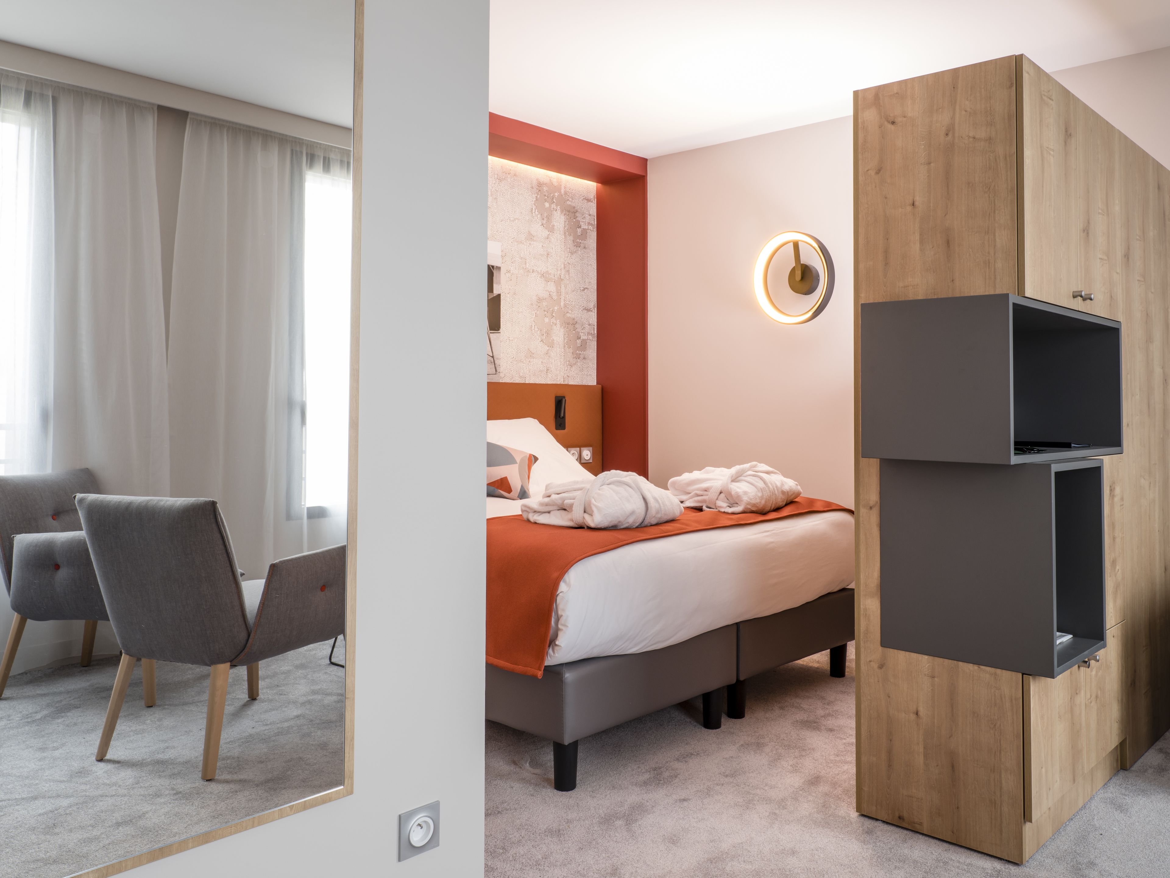 Una habitación de hotel moderna con una cama, un armario de madera, un escritorio y una silla.