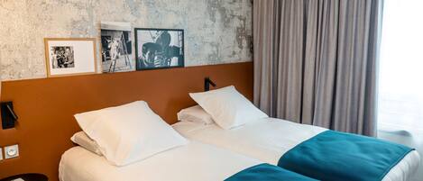 Una cama doble con ropa de cama blanca y aguamarina, un cabecero y una pared con dos fotografías enmarcadas.