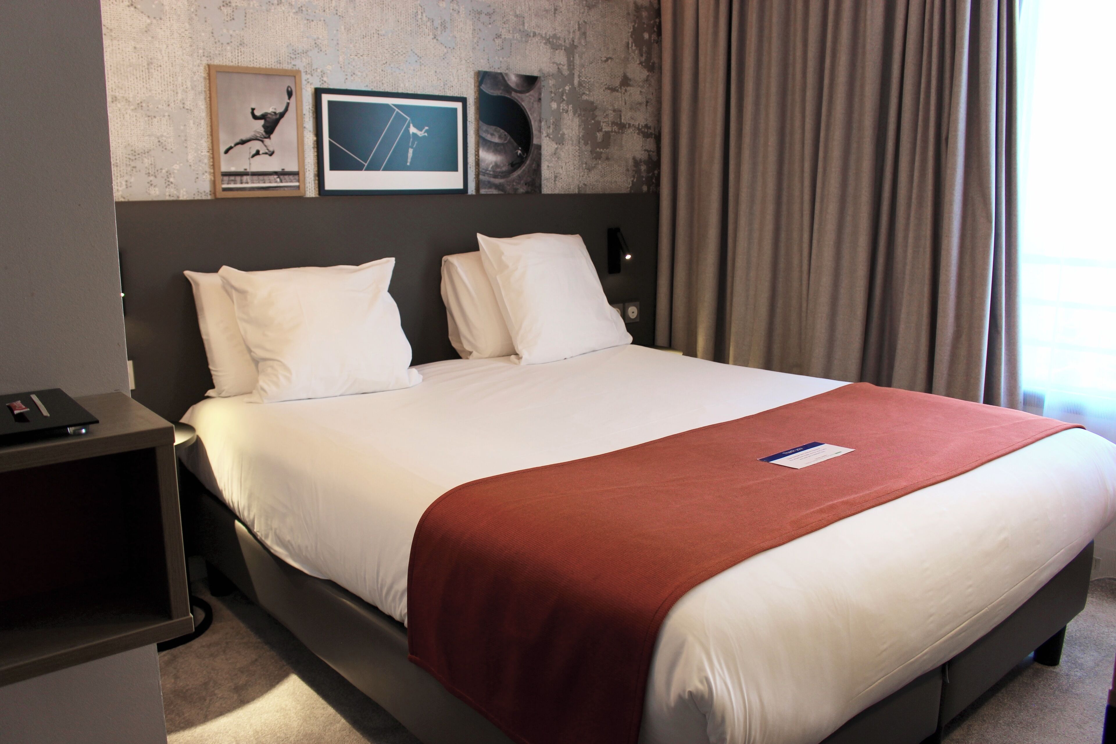 Una habitación de hotel con una cama grande, una mesita de noche y una pared decorada con cuadros.