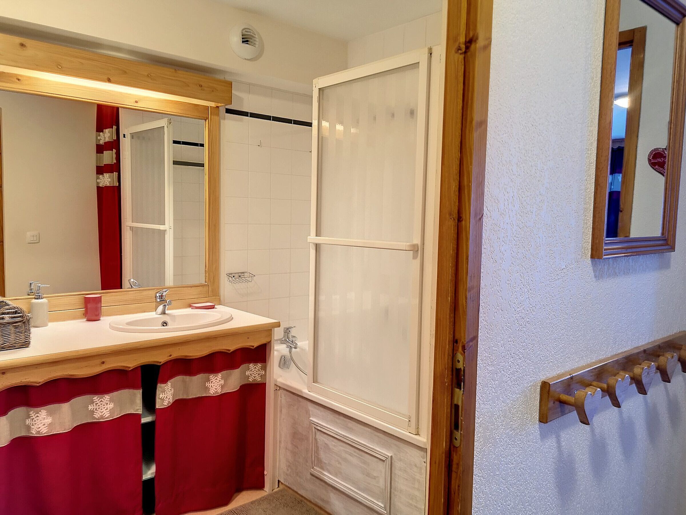 Une salle de bain avec un meuble-lavabo en bois, un miroir, une douche et un porte-serviettes.
