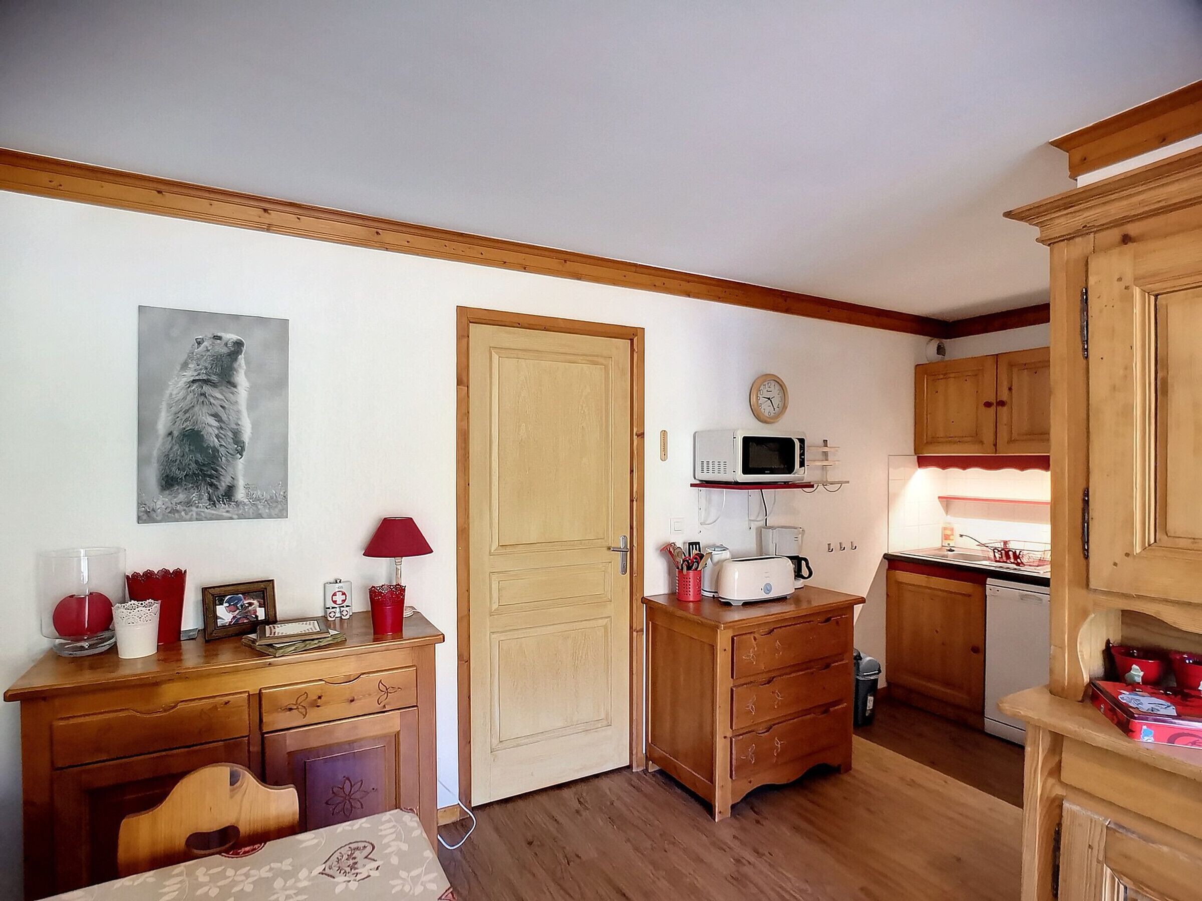 Une petite cuisine accueillante, avec des meubles en bois, un four à micro-ondes, une machine à café et un coin repas comprenant une table et des chaises.