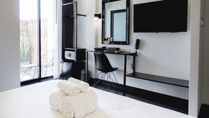 A modern hotel room with a large bed, a desk with a chair, a flat-screen TV mounted on the wall, and an air conditioning unit. - iSilver Hotel (Chiang Mai)