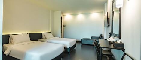 A hotel room with two beds, a desk, a chair, and a mirror.