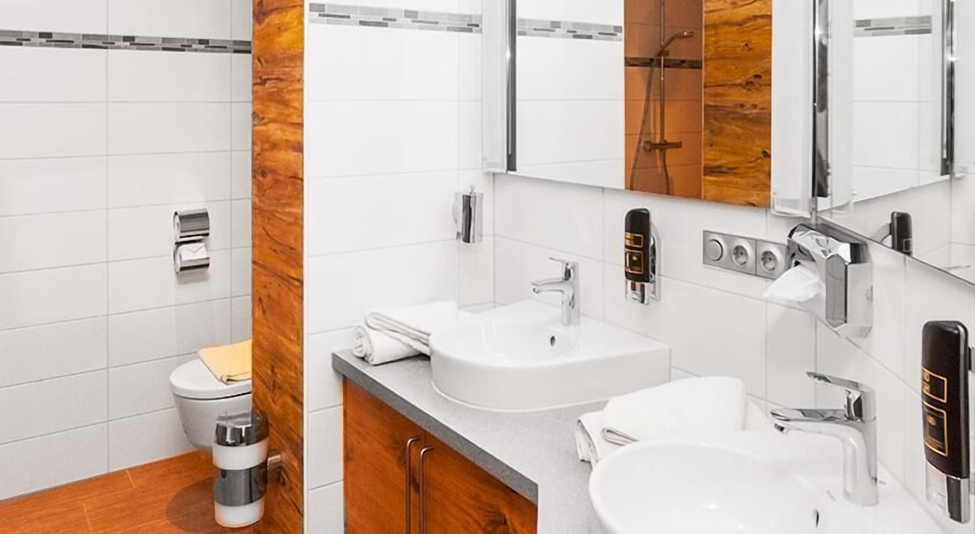 Un baño moderno con inodoro, bidé y dos lavamanos.