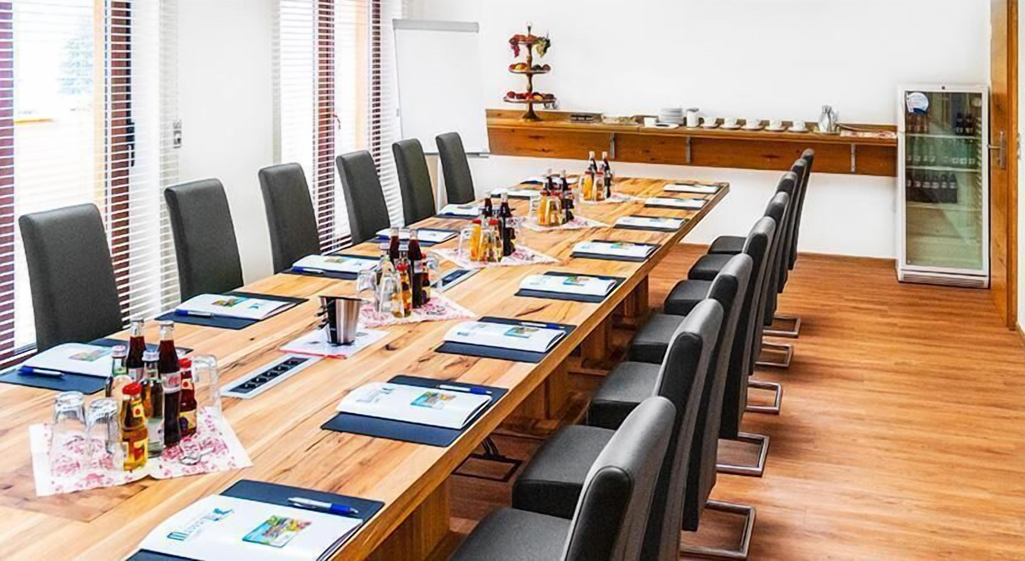 Ein Konferenzraum mit einem langen Tisch, Stühlen und einem Kühlschrank im Hintergrund.