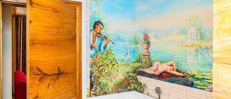 Ein Badezimmer mit Wandgemälde einer friedlichen Landschaft, einer Holztür und einem roten Stuhl.