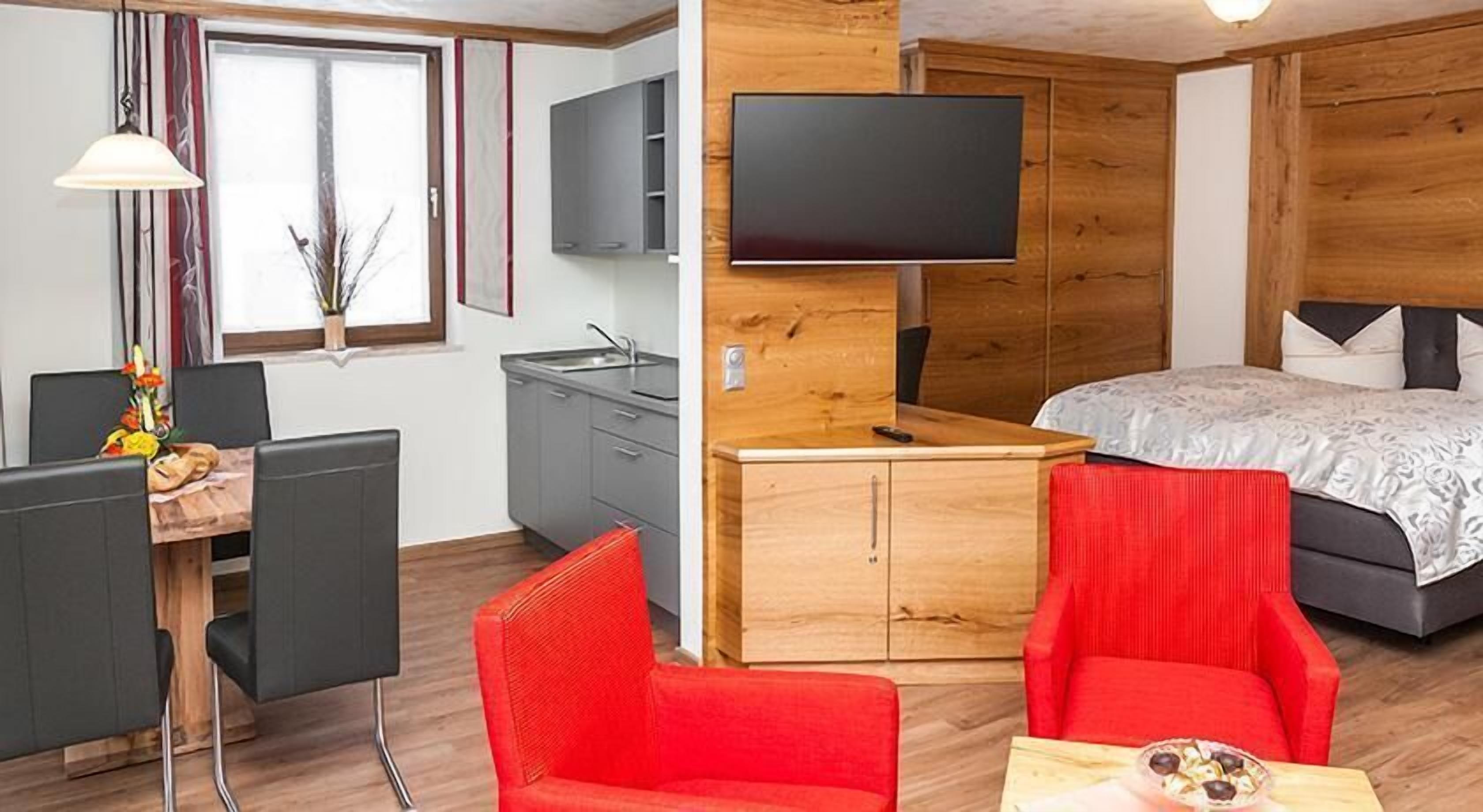 A compact hotel room with a desk, a chair, a bed, and a TV.