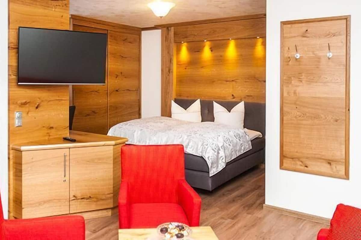 Una habitación de hotel compacta con cama, televisión, escritorio y armario.
