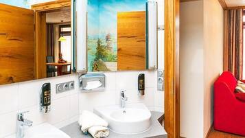 Un baño moderno con dos lavamanos, un espejo y una silla roja.