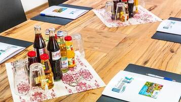 Une table de conférence avec diverses boissons et un carnet illustré aux couleurs vives.