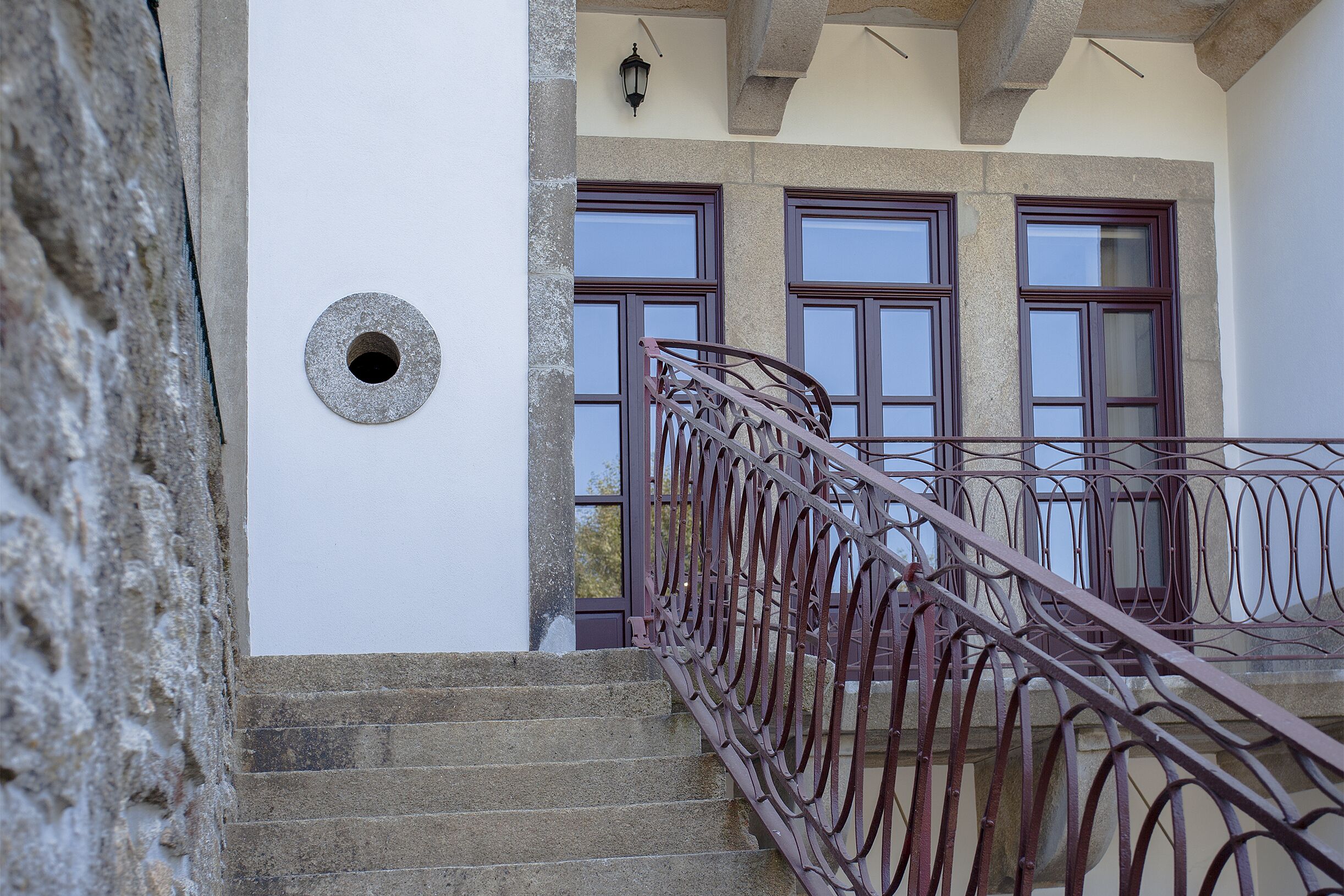 A staircase with a metal railing leading to a balcony with large windows.