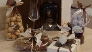 Una mesa con una botella de licor, un vaso, un tarro de nueces y regalos envueltos.