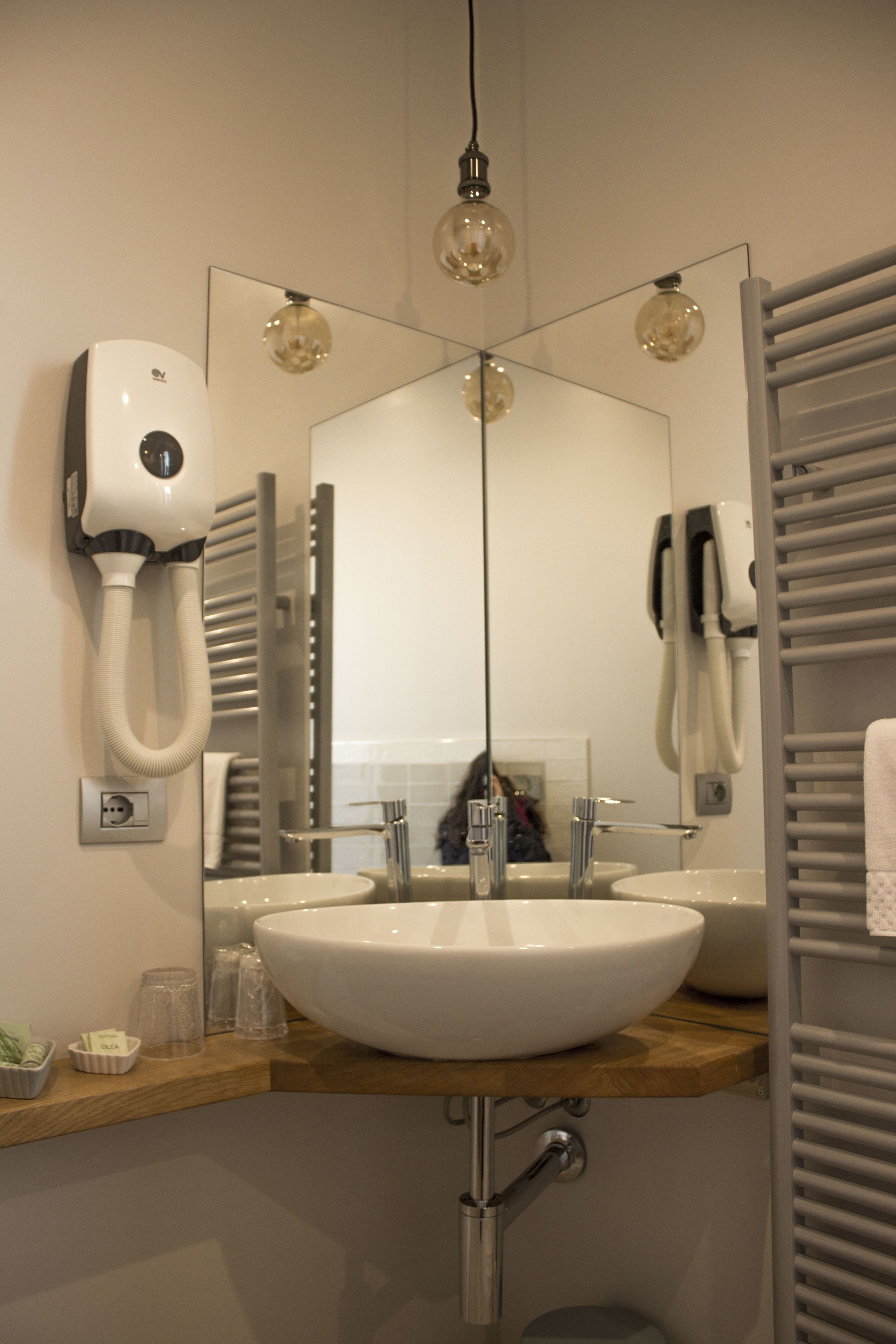 A bathroom with a white sink, a mirror, a hairdryer, and a towel rack.