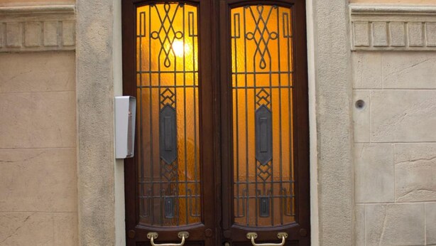 Una doble puerta de madera con ornamentación metálica detallada y una cabeza de león en la parte superior.