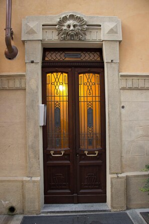 A double wooden door with intricate metalwork and a lion's head above it. - Palazzo Belli (Alba)