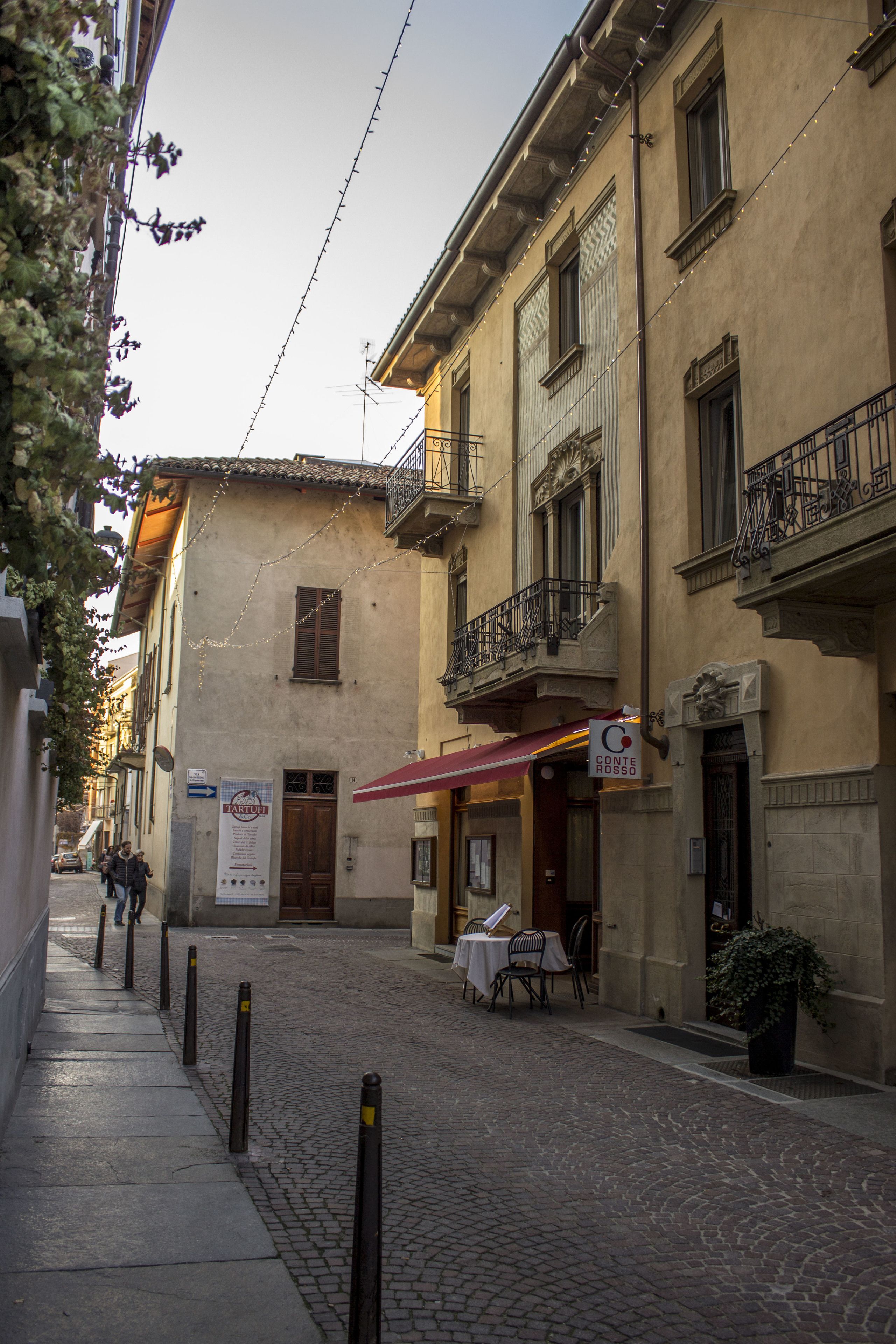 Une rue pavée, avec un restaurant appelé « Conte Rosso » situé à l’angle.